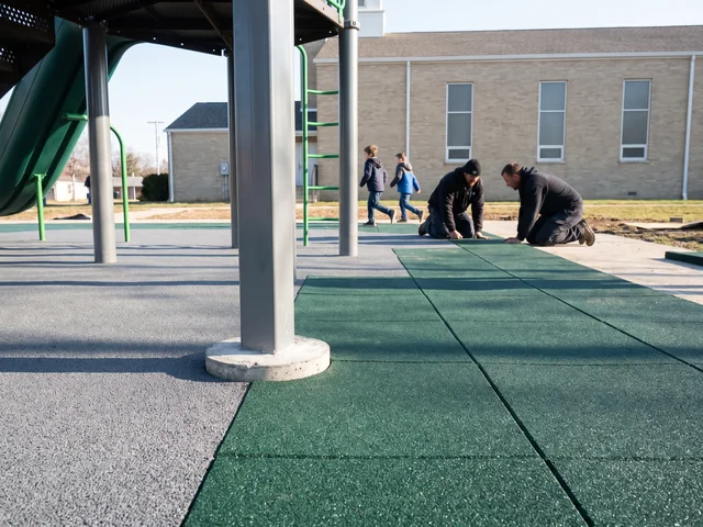 Poured EPDM surfacing meeting rubber tiles under a play structure