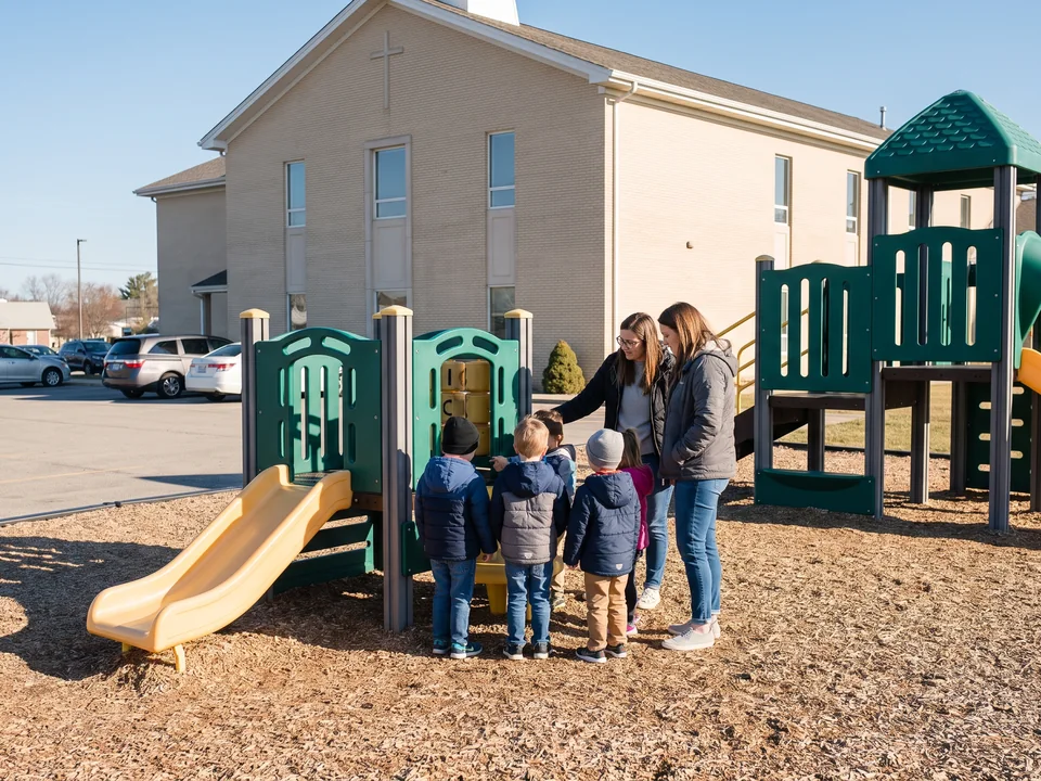 Two teachers with a small group of young children at a low play structure on a weekday morning
