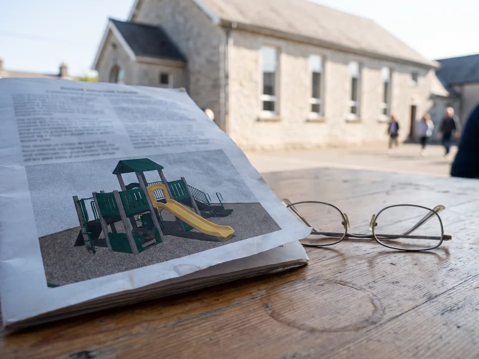 Printed bulletin page with a playground render on a table
