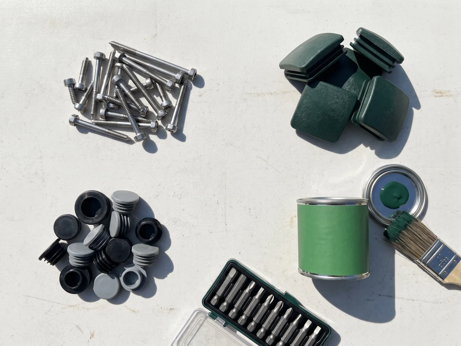 Spare kit laid out: stainless fasteners, post caps, plugs, touch-up paint and security bits