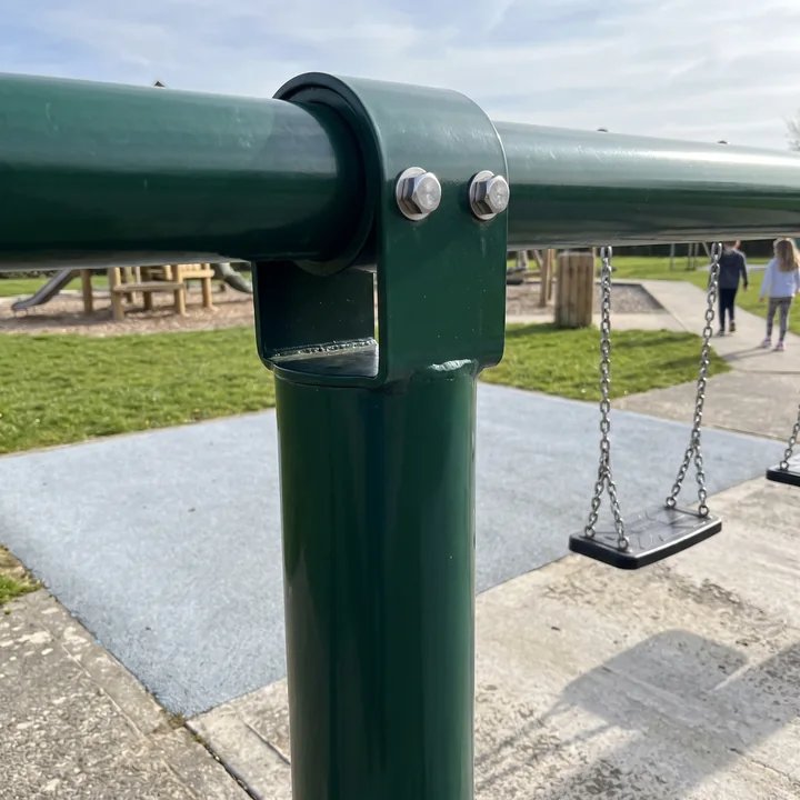 A welded saddle bracket on top of an evergreen swing post holding the beam, with two capped 304 bolts