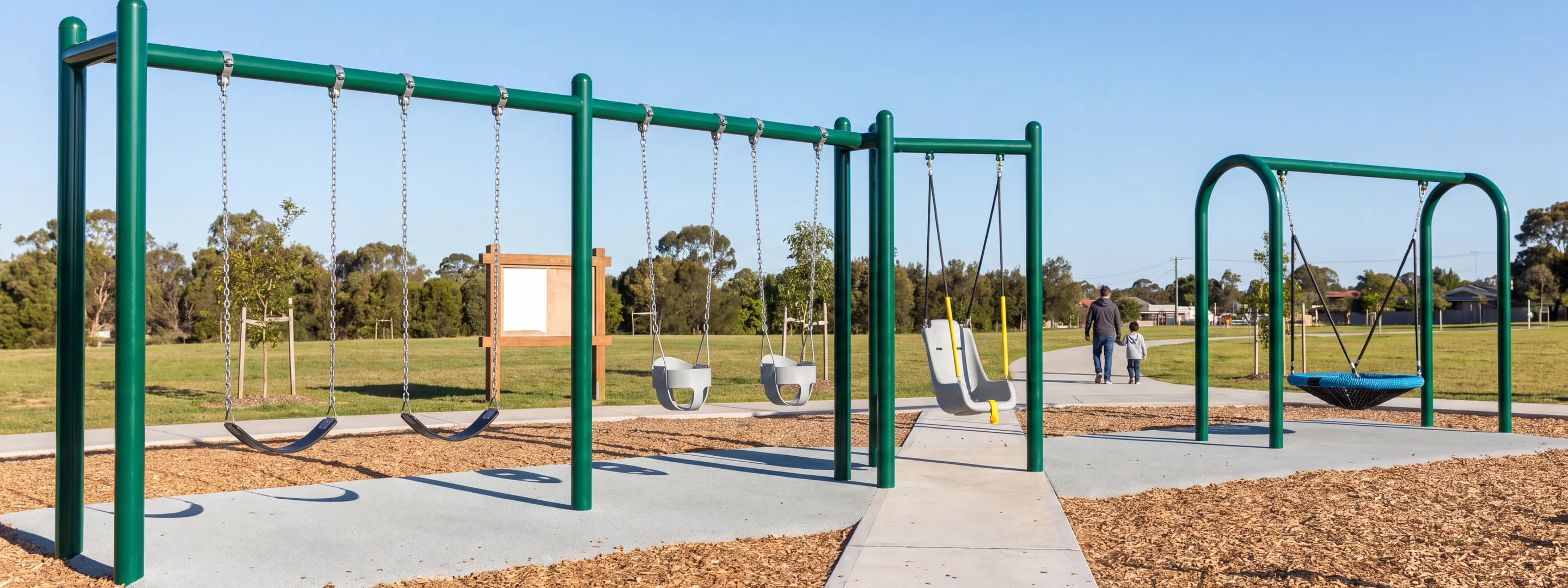 A park with a belt bay, a toddler bucket bay, a high-back bay and a separate nest swing frame side by side in morning light, a parent and child seen from behind in the distance