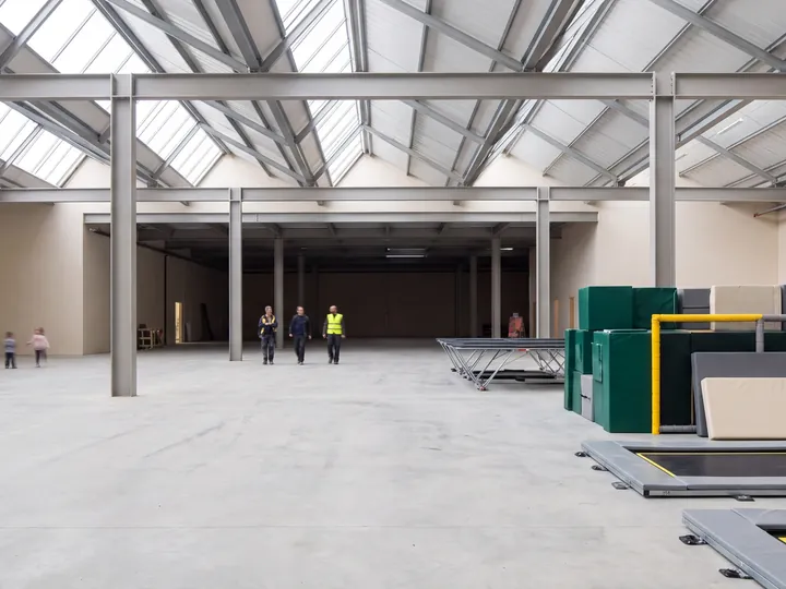An empty skylit warehouse hall with rows of columns, ready for an indoor play venue fit-out