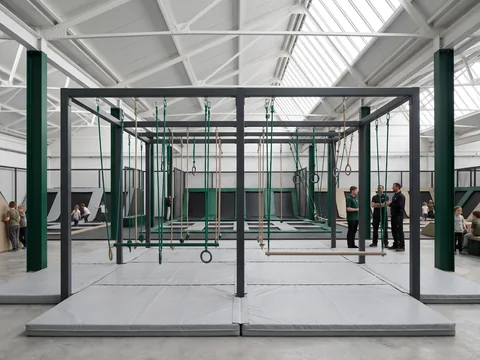 Charcoal steel ninja course frame with rings, ropes and bars over light grey landing mats