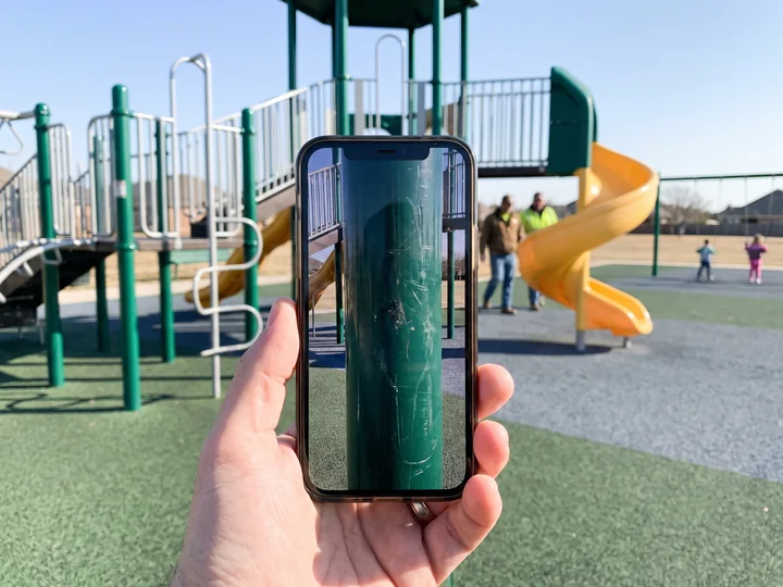 A phone showing a photo of a damaged playground post