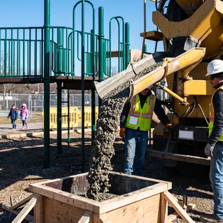 Concrete footing being poured for a playground post