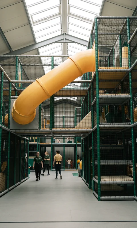 Multi-level commercial soft play structure with netting and a tube slide