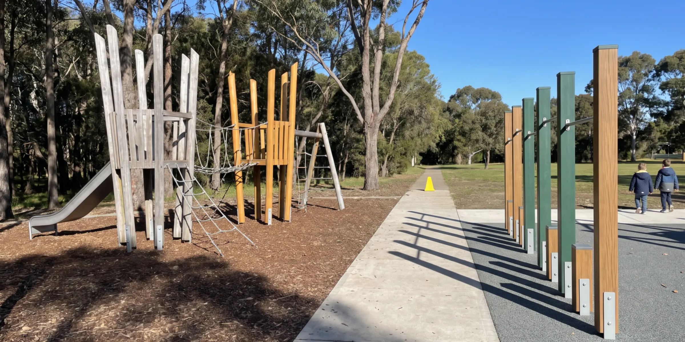 One park site: Robinia climbing frames in the woodland corner on the left, timber-look and evergreen steel posts along the paved path on the right