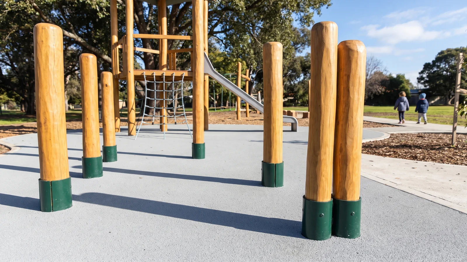 Poured rubber surfacing under a Robinia tower, every evergreen steel shoe showing above the finished surfacing level
