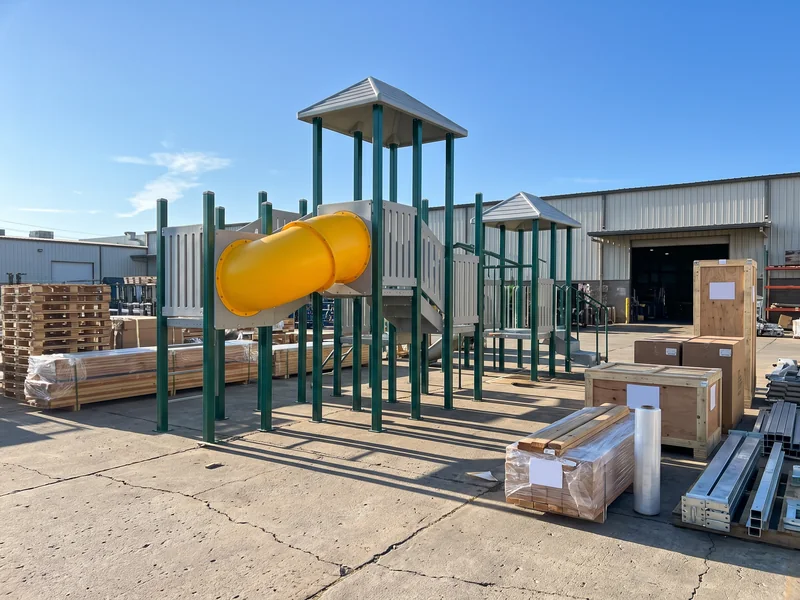 A pre-assembled multi-deck commercial play structure standing in the factory yard before packing