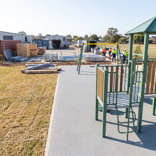 A new playground beside an empty lawn area marked out with white line for a second phase