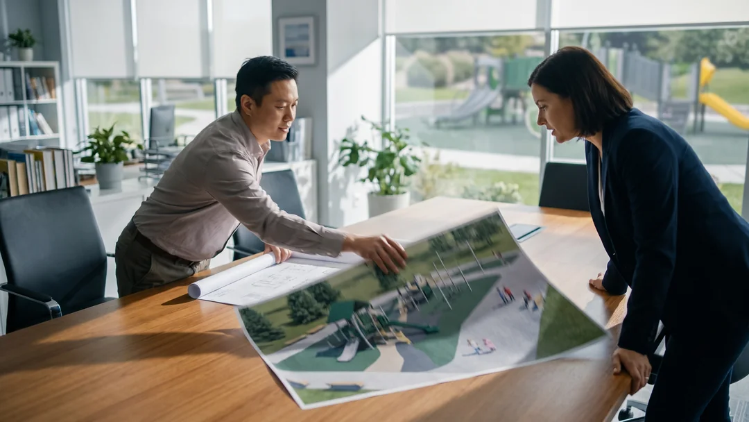 A dealer presenting a printed plan set and render to a client across a meeting table