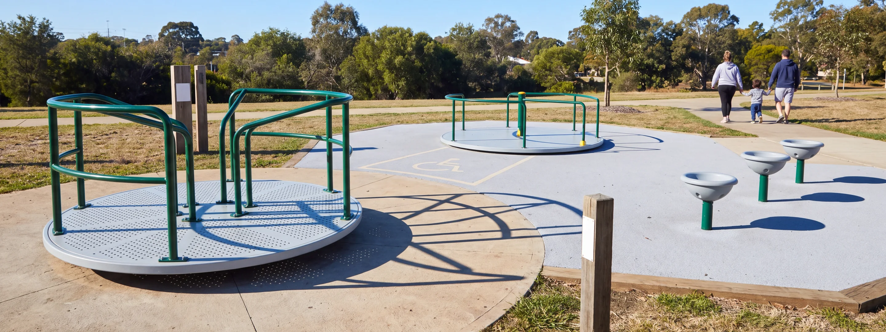 A park with a classic merry-go-round, a ground-level inclusive spinner and a row of single-user spinners