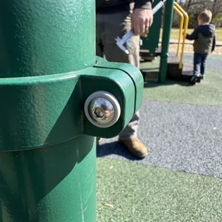 A capped tamper-resistant stainless fastener on a steel post