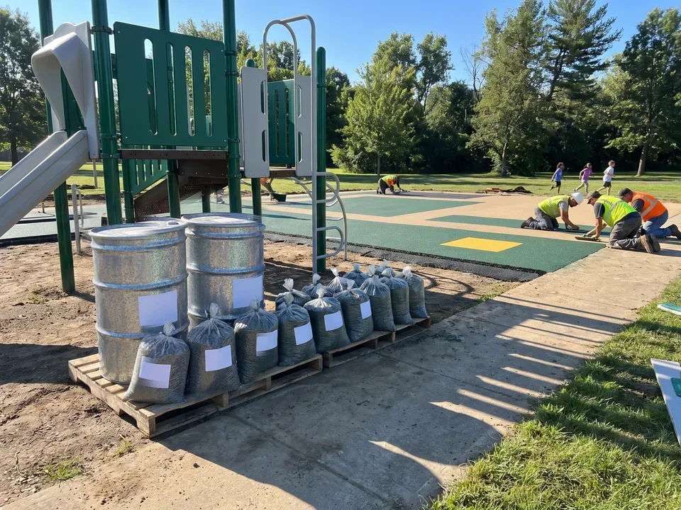 Granule bags and two PU binder drums with blank labels on a job site