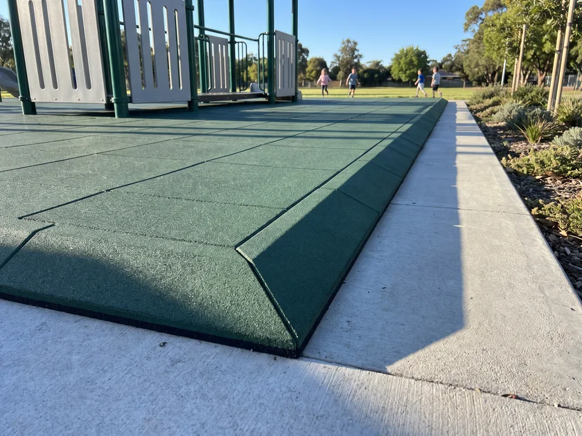 Evergreen beveled ramp edge pieces and a mitred corner piece taking a rubber tile area down to a concrete path
