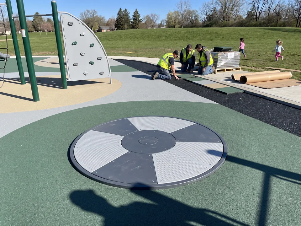 Ground-level spinner sitting flush in poured-in-place surfacing with a neat pit edge