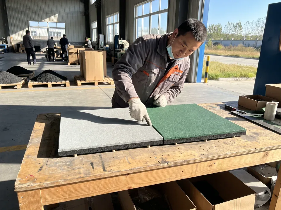 Two sample tiles joined with dowel pins while a QC inspector checks the joint is level