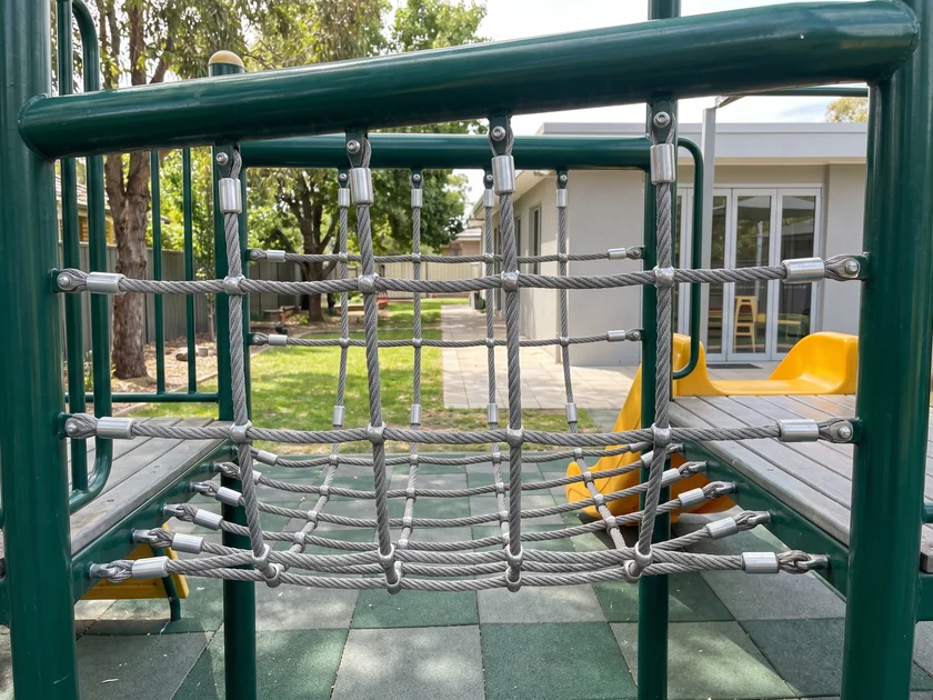 A net panel climbing to a low deck of a play structure