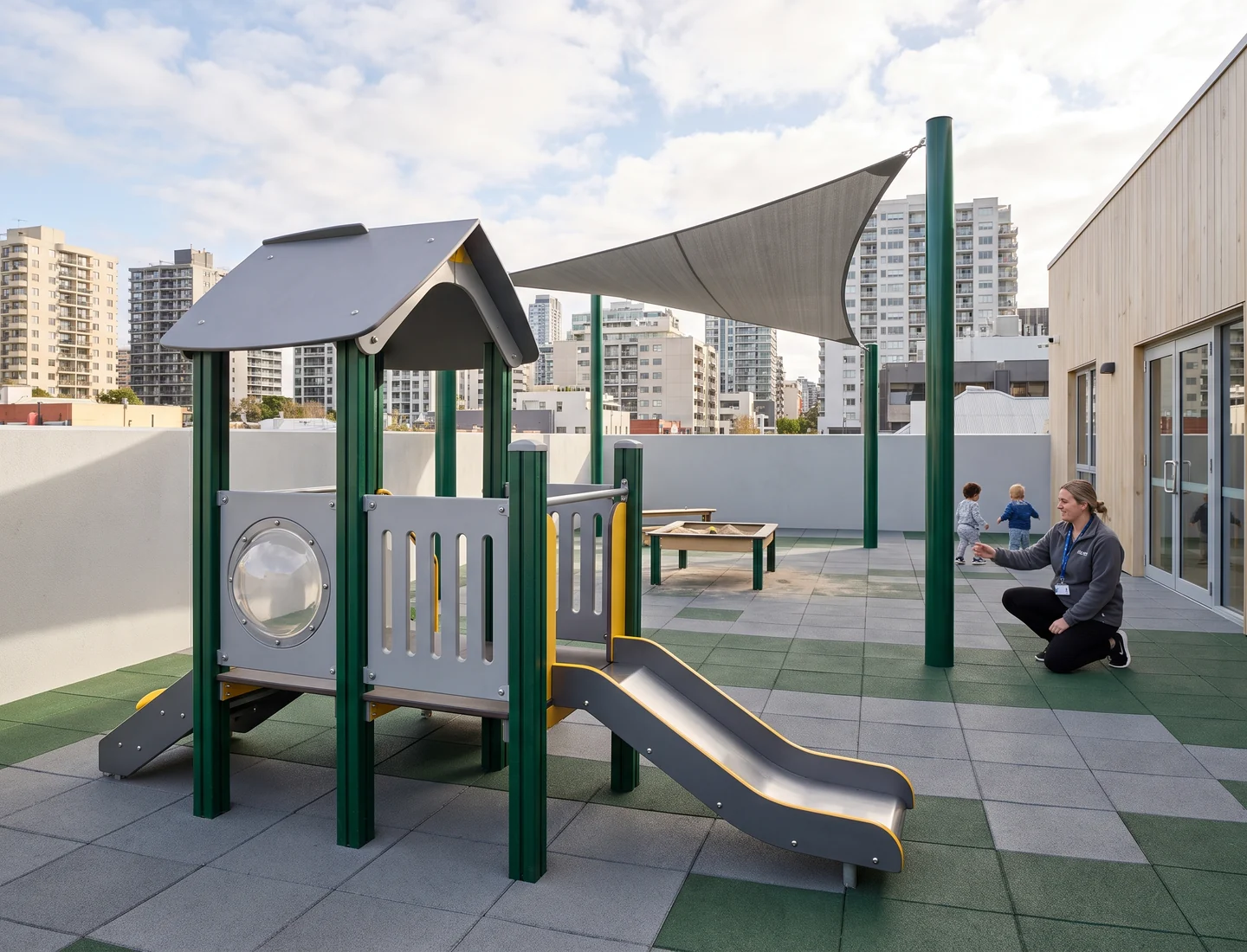 Rooftop daycare play area with a low-deck structure and a shade sail