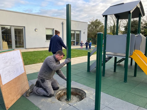 Installer setting a post in a daycare yard
