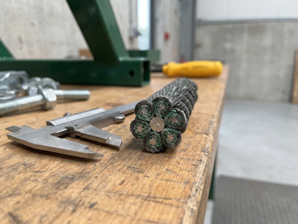 A cut end of 16 mm six-strand polyester rope showing the steel wire core, beside a caliper