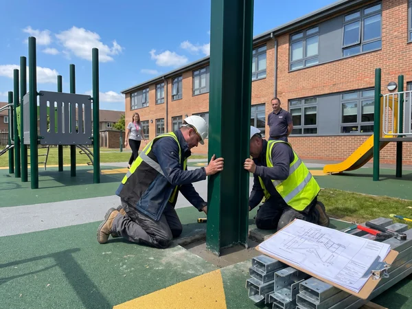 Installer setting a numbered post on a school playground