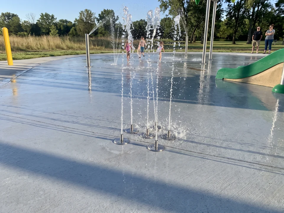 Flush ground spray nozzles set in a concrete splash pad throwing straight jets of water