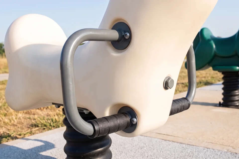 A powder-coated steel handle with black grips bolted through a rotomolded rider body, bolt heads capped