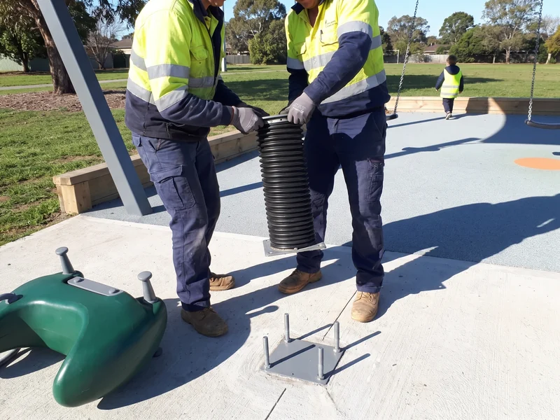 Two crew members lifting the old spring set off the anchor plate while the surfacing stays intact