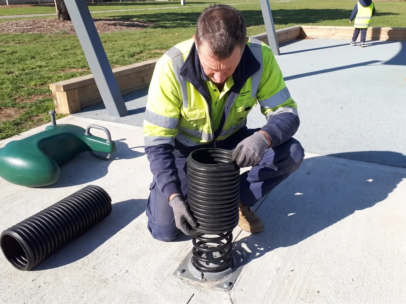 A crew member sliding the pinch-guard sleeve over a new spring set bolted to the anchor plate