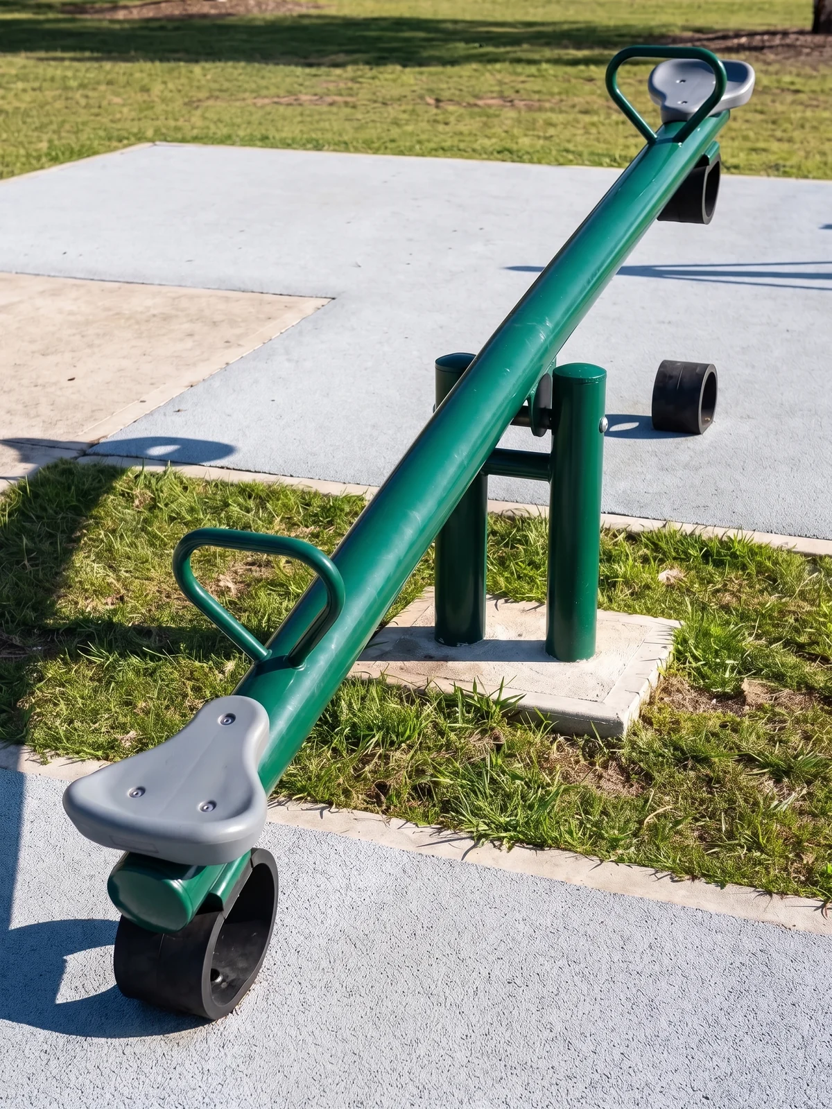 An evergreen classic beam seesaw in a park, one seat end resting on its rubber bumper