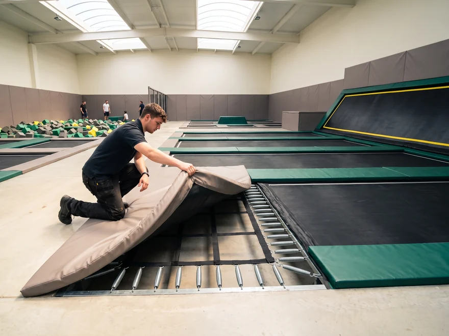 Staff member lifting a spring-cover pad to look at the springs