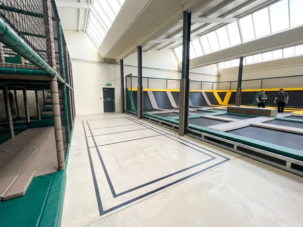 Empty floor area beside an existing soft play venue with columns and a fire exit